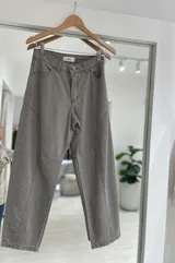 Jean de corte baggy en color gris, con diseño de costuras verticales y paneles en las piernas. Cuenta con cierre de botón metálico y bolsillos laterales.