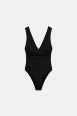 Body de poliamida color negro con escote en pico, tirantes anchos y detalle de tejido drapeado en la cintura. Presenta espalda abierta y cierre inferior con botones a presión.