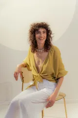 Top de lino color mostaza, con escote en V profundo anudado al frente, mangas cortas amplias y puños con volado.