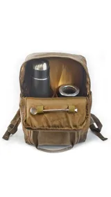 Mochila urbana de tela canvas color marrón, con diseño funcional que incluye compartimento para notebook de 15 pulgadas y espacio interior organizado para set de mate. Cuenta con correas ajustables, manija superior reforzada, bolsillo frontal con cierre y detalles en cuero sintético.