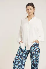 Camisa blanca de manga larga con cuello clásico y cierre frontal con botones.