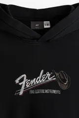 Sudadera con capucha y bolsillo canguro, color negro lavado, con estampado frontal que incluye el logo de Fender y un sombrero de vaquero.
