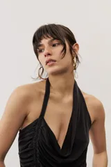 Top negro con diseño cruzado tipo halter, escote pronunciado y fruncido lateral.