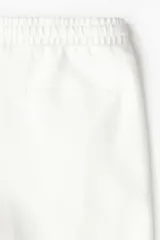 Jogger color blanco hueso en tejido suave de mezcla de algodón, con pliegue cosido en la parte delantera. Presenta cierre decorativo, cintura elástica con cordón ajustable, bolsillos laterales y un bolsillo insertado en la parte trasera. Corte estándar.