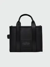 Cartera tipo tote de cuero rojo de la marca Marc Jacobs, modelo The Leather Small Tote Bag. Presenta doble asa superior, correa ajustable y extraíble para el hombro, y el texto grabado en relieve "THE TOTE BAG MARC JACOBS" en el frente.