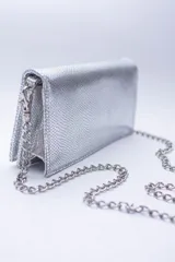 Cartera negra con textura símil cocodrilo y cadena metálica plateada.