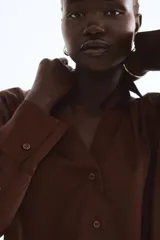 Blusa de manga larga color marrón oscuro, con cuello clásico y escote en V profundo, cierre frontal de botones y puños anchos.