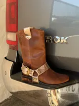 Bota de cuero marrón con estribo desmontable plateado.