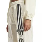 Pantalón deportivo Adidas color crema, con cintura elástica, corte ancho y tres rayas negras verticales en los laterales.