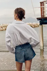 Shorts de jean tiro medio, corte mom fit, con bajo deshilachado y forro de bolsillos delanteros estampado a cuadros que asoma por debajo.