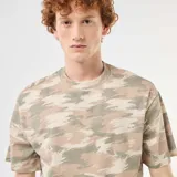 Remera de algodón con cuello redondo y estampado de camuflaje en tonos verde militar, beige y marrón, de corte relajado y mangas cortas.