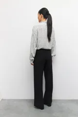 Pantalón de vestir negro de corte ancho y tiro alto, con elástico en la cintura y costuras verticales decorativas a lo largo de las piernas.