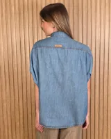 Camisa de denim liviano color azul, de mangas cortas amplias y corte oversize. Presenta cuello camisero clásico y cierre frontal con botones.