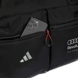 Bolso deportivo híbrido Adidas Audi Revolut F1 Team negro, fabricado en tejido CORDURA® resistente al desgaste. Cuenta con un compartimento principal amplio, bolsillos exteriores con cierre y correas de transporte ajustables.