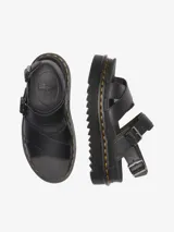 Sandalia Dr. Martens Voss II Athena de dos correas, color negro, con diseño minimalista y elegante. Confeccionada en cuero Athena recubierto de PU, cuenta con una suela Quad Zebrilus de 3 pulgadas y dos hebillas de metal en el tobillo para un ajuste cómodo. Presenta la costura amarilla característica de Dr. Martens.