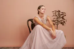 Vestido largo de tul plumetí en color rosa suave, con detalles de encaje bordado en el torso y volados en los hombros.