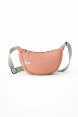 Bandolera tipo riñonera en forma de media luna, color salmón, con cierre de cremallera y correa ajustable de tela color verde claro. Incluye etiqueta con la marca "INDIAN".