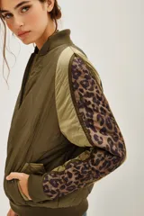 Campera tipo bomber acolchada en color verde militar, con mangas largas que presentan paneles laterales con estampado animal print. Cuenta con cierre frontal, cuello, puños y ruedo en tejido rib elástico.