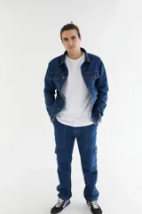 Campera de jean azul con cuello clásico, cierre frontal con botones metálicos, dos bolsillos con solapa abotonada en el pecho y dos bolsillos laterales.