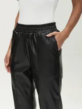 Pantalón negro de cuero sintético con cintura elástica y corte recto.