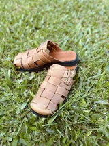 Sandalias suecos color camel con tiras de cuero trenzado, hebilla metálica y suela de goma negra.