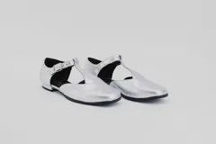 Zapato flat color ladrillo de cuero, con corte en forma de T y hebilla dorada.