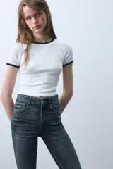 Jeans skinny de tiro alto en color negro, confeccionados en tejido super elástico de cinco bolsillos, con cierre frontal de cremallera y botón metálico.