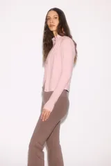 Campera deportiva rosa de corte ajustado, con cuello elevado, cierre frontal completo y mangas largas con abertura para el pulgar.