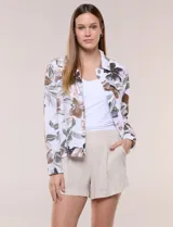 Camperita de lino liviana, marca Dash, con estampado botánico de hojas en tonos azules, verdes y tostados sobre base blanca. Presenta cierre frontal con botones, cuello clásico y bolsillos aplicados en el pecho.