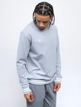 Buzo negro de corte clásico con cuello redondo, puños y ruedo acanalados con doble línea blanca. Logo de Umbro bordado en el pecho. Mangas con paneles laterales en gris. Confeccionado en algodón y poliéster.