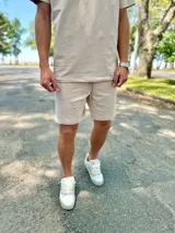 Conjunto deportivo beige compuesto por una remera de manga corta con cuello redondo y un short a juego con cordón ajustable.