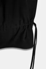 Pantalón de tiro medio con diseño cargo, confeccionado en tejido con mezcla de lana. Presenta bolsillos laterales de plastrón y bajo abullonado ajustable mediante lazadas. Cierre frontal con cremallera, botón y ganchos metálicos.