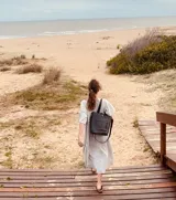 Bolso tipo matera de color negro, diseñado para transportar el equipo de mate con la funcionalidad de una cartera. Cuenta con un bolsillo exterior frontal, correas de hombro y una correa larga ajustable y extraíble. El interior está forrado con material impermeable.