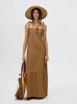 Vestido midi de denim color marrón, con corte holgado, breteles finos con lazos ajustables y detalle de volado en el ruedo.