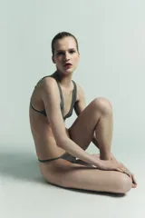 Tanga de tiro medio color gris oscuro, con cintura elástica y paneles laterales de tul semitransparente en tono rosado pálido.