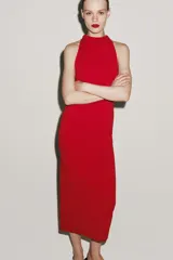 Vestido largo negro de cuello halter fluido, con detalle de drapeado lateral y espalda descubierta.