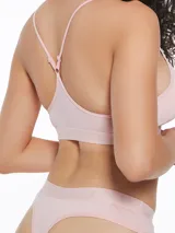 Top deportivo tipo bralette negro, con escote en V y tirantes finos cruzados en la espalda. Presenta una banda elástica ancha bajo el busto con texto repetido.