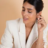 Medio aro de oro 18k con perla de cultivo colgante. Diseño minimalista y elegante.