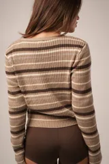 Cárdigan corto tejido en punto canalé color verde con rayas horizontales marrones y crudas, escote en V y cierre frontal con botones al tono.