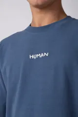 Remera oversize de algodón pesado color azul, con bordado "HUMAN" centrado en el pecho y hombros ligeramente caídos.