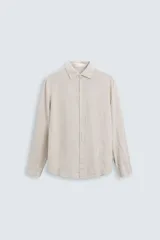 Camisa de corte regular fit confeccionada en tejido de lino, con cuello solapa, manga larga con puños abotonados y cierre frontal de botones.