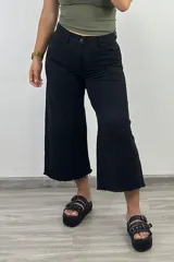 Pantalón jean negro de corte culotte con terminación desflecada.