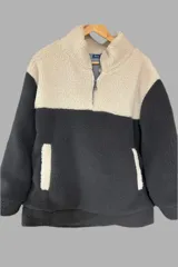 Buzo de polar con cierre a la mitad, color negro y beige.