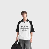 Remera polo oversize de manga corta estilo raglán, en combinación de color blanco en el torso y negro en las mangas y el cuello. Cuenta con un estampado gráfico frontal con inscripciones y tipografía cursiva.