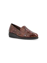 Zapato tipo mocasín slip-on con acabado en cuero charol texturizado con efecto reptil en tonos marrones. Presenta una suela de plataforma plana de color negro con diseño dentado y una estructura anatómica para mayor confort.