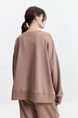 Buzo de felpa color marrón con estampa frontal en rosa, cuello redondo y hombros caídos.