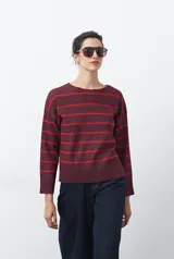 Sweater de tejido de punto con diseño de rayas horizontales en tonos bordó y rojo. Presenta cuello redondo, mangas largas con hombros caídos y terminaciones acanaladas en puños, cuello y ruedo.