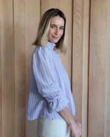 Blusa de algodón con cuello mao y volados, mangas largas con puños elásticos y corte holgado.