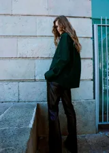 Camisa oversize de algodón en color verde oscuro, con cuello camisero, cierre frontal de botones, bolsillo de parche en el pecho y mangas largas con puños abotonados.