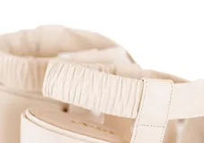 Sandalia de taco ancho medio con diseño de tiras cruzadas acolchadas en el empeine y talonera elástica fruncida. Presenta punta cuadrada y suela de cuero natural.